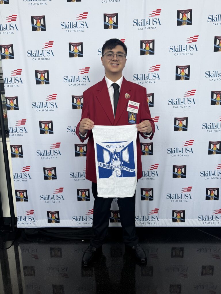 JC en SkillsUSA California, sosteniendo una pancarta azul y blanca.