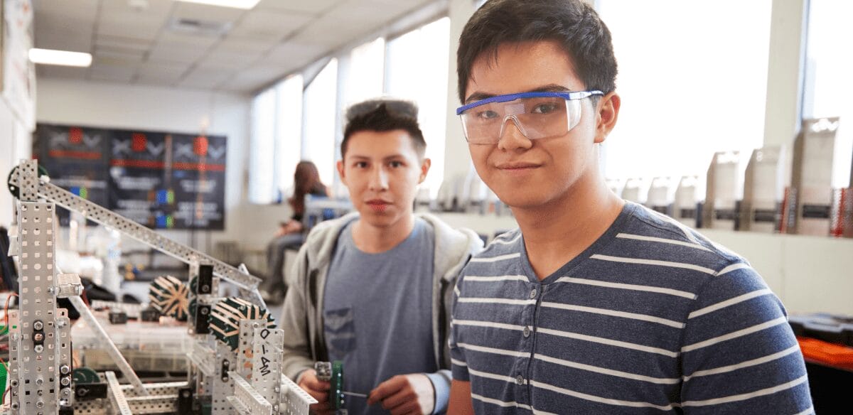 Dos jóvenes colaboran en un laboratorio, examinando un robot como parte de sus esfuerzos de investigación científica e innovación.