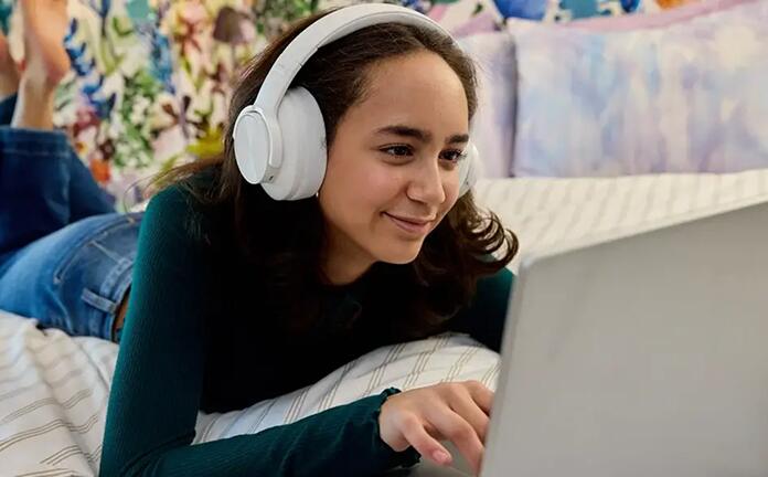 Un estudiante de secundaria que asiste a una clase en línea con unos auriculares blancos puestos